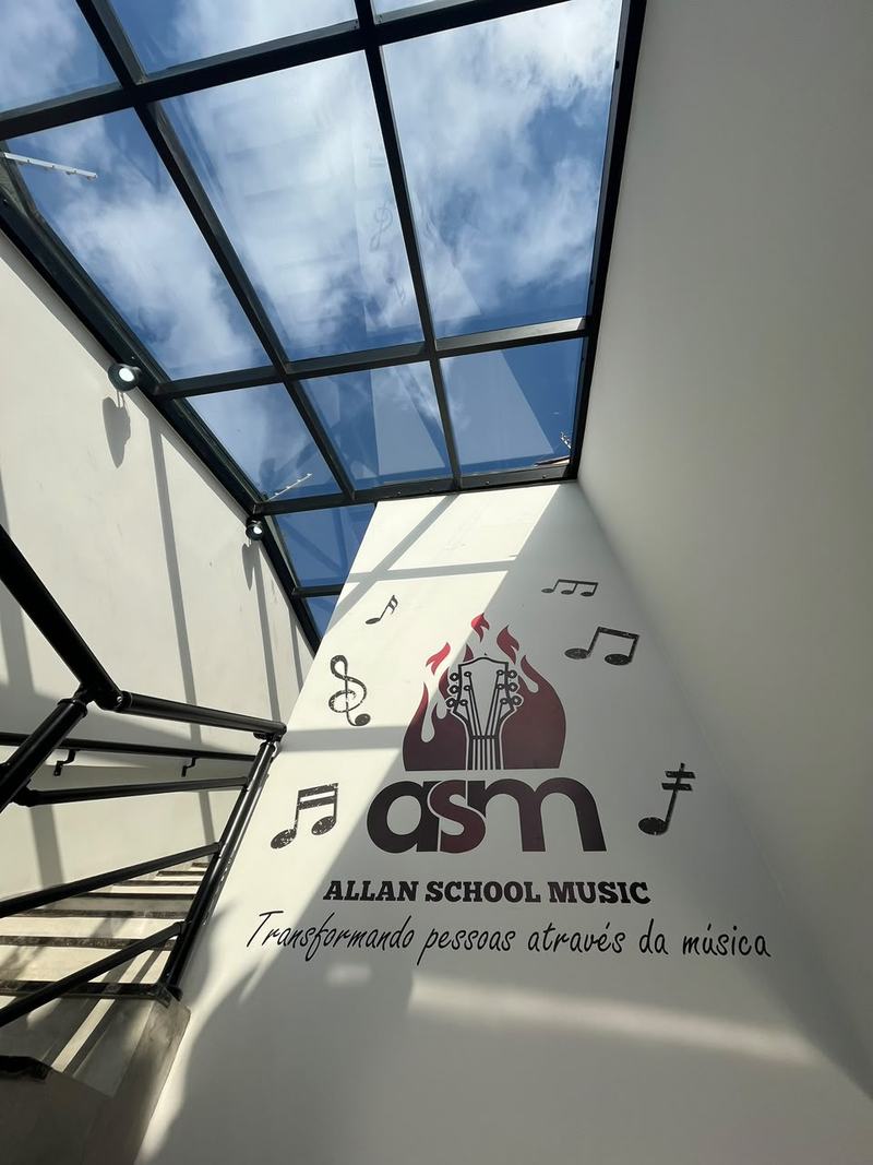 Escada da escola com o logo da ASM pintado na parede e o lema Transformando pessoas através da música