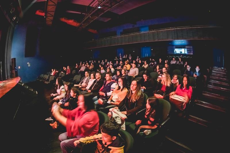 Plateia de uma apresentação da ASM com famílias e crianças assistindo